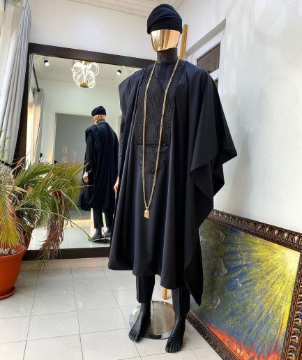 A charcoal black agbada, Jesus piece long fashion chain and hand woven aso oke Yoruba hat.
