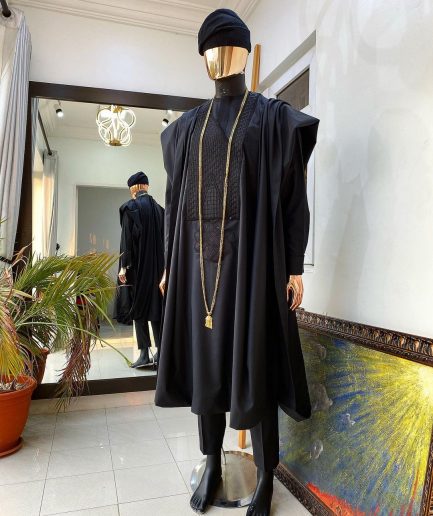A charcoal black agbada, Jesus piece long fashion chain and hand woven aso oke Yoruba hat.