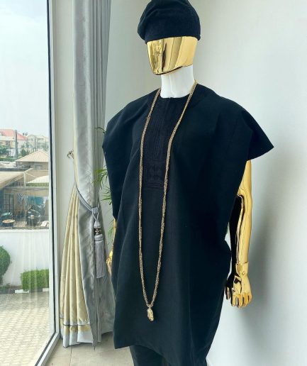 A charcoal black aso dashiki with a floral and box-shaped embroidery design, a hand-weaved Yoruba hat, and a gold Jesus timepiece
