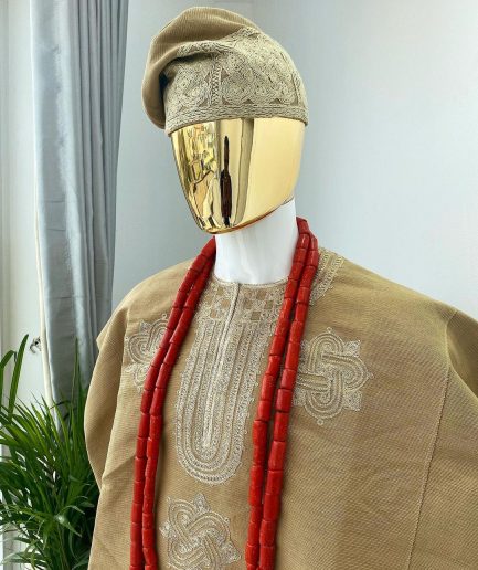 A champagne gold aso oke dashiki, with a floral and ancient style shaped embroidery design, hand woven Yoruba hat, an extra length red and gold coral bead.