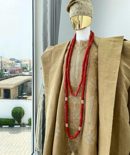 A champagne gold aso oke regal agbada, dashiki, sokoto, red and gold mix coral bead, matching hand woven Yoruba hat, and a long gold chain with a Jesus piece.