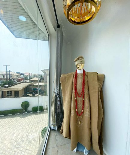 A champagne gold aso oke regal agbada, dashiki, sokoto, red and gold mix coral bead, matching hand woven Yoruba hat, and a long gold chain with a Jesus piece.