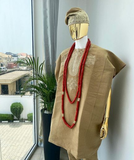A champagne gold aso oke dashiki, with a floral and ancient style shaped embroidery design, hand woven Yoruba hat, an extra length red and gold coral bead.
