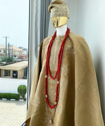 A champagne gold aso oke regal agbada, dashiki, sokoto, red and gold mix coral bead, matching hand woven Yoruba hat, and a long gold chain with a Jesus piece.