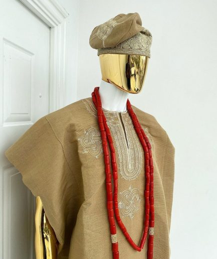 A champagne gold aso oke dashiki, with a floral and ancient style shaped embroidery design, hand woven Yoruba hat, an extra length red and gold coral bead.