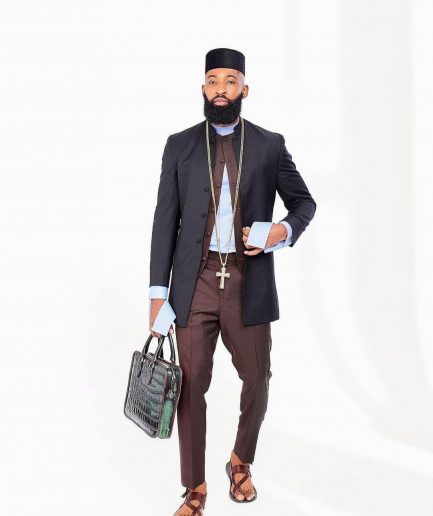 A Reloaded Ceremonial “Ayeye” Ijade 20/21 - Look 10- “Ajala”. A burgundy safari jacket with gold buttons, inner waist coat, turtle neck shirt, hat and pant trousers.
