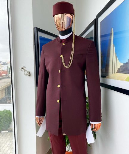 A Reloaded Ceremonial “Ayeye” Ijade 20/21 - Look 10- “Ajala”. A burgundy safari jacket with gold buttons, inner waist coat, turtle neck shirt, hat and pant trousers.