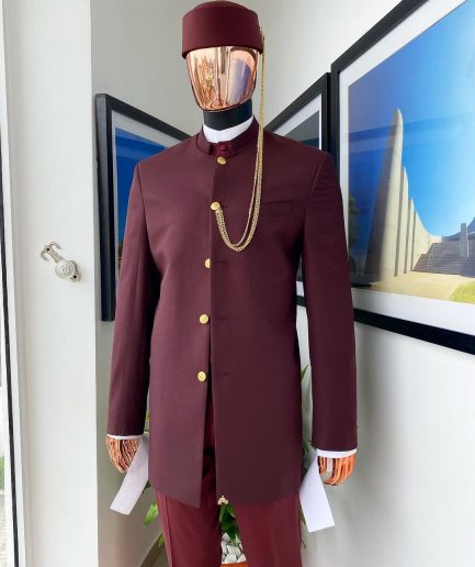 A Reloaded Ceremonial “Ayeye” Ijade 20/21 - Look 10- “Ajala”. A burgundy safari jacket with gold buttons, inner waist coat, turtle neck shirt, hat and pant trousers.