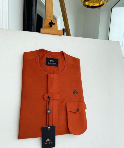 A fire orange, double vertical flap with horizontal closed detailing, combat pocket, and Swarovski button details African traditional senator kaftan native
