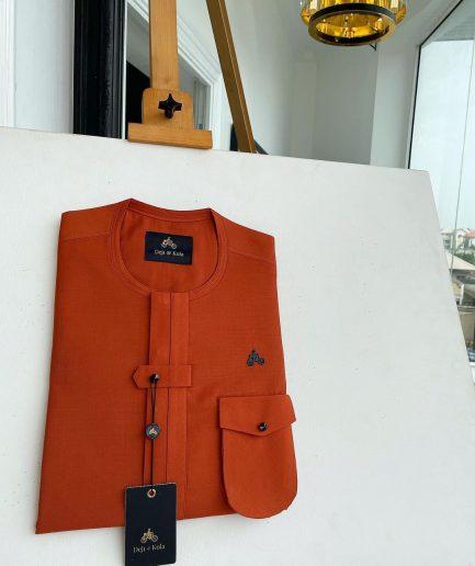 A fire orange, double vertical flap with horizontal closed detailing, combat pocket, and Swarovski button details African traditional senator kaftan native